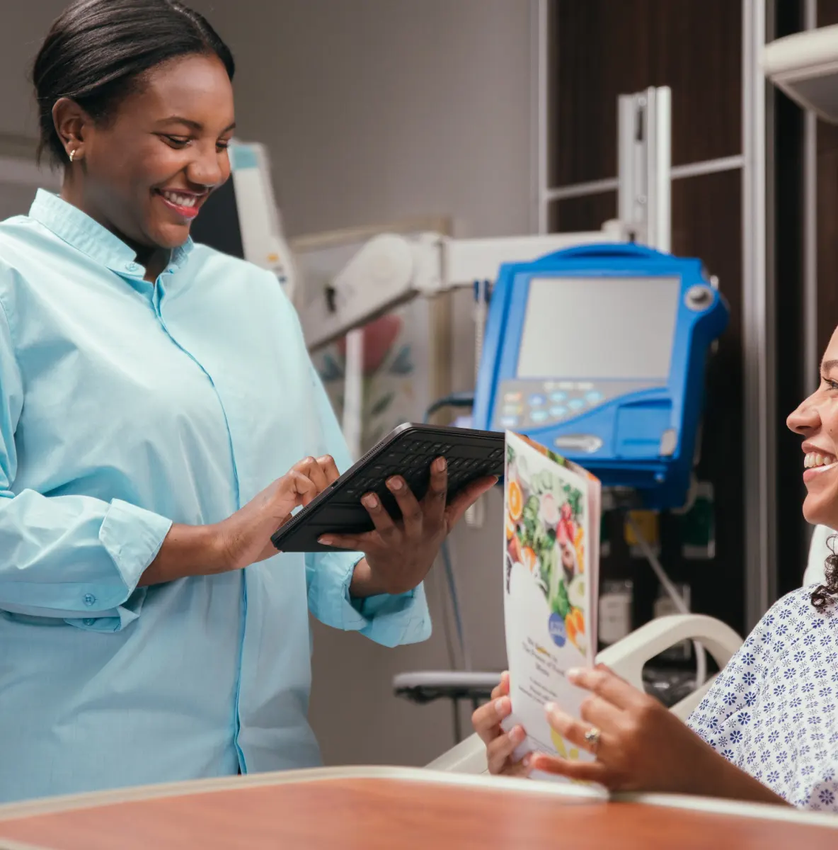 Smiling healthcare worker using digital tablet in hospital room